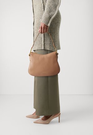 Tan leather handbag with a curved shape, gold hardware, and a shoulder strap. Paired with a textured beige sweater and olive green pants.
