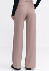 Jasnoróżowe spodnie o szerokich nogawkach z gładkiej tkaniny, z wysokim stanem, dwoma tylnymi kieszeniami i dopasowanym krojem.
