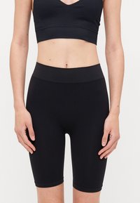 Black bike shorts made of stretchy fabric, featuring a high waistband and knee-length cut, smooth texture with no visible patterns or accents.