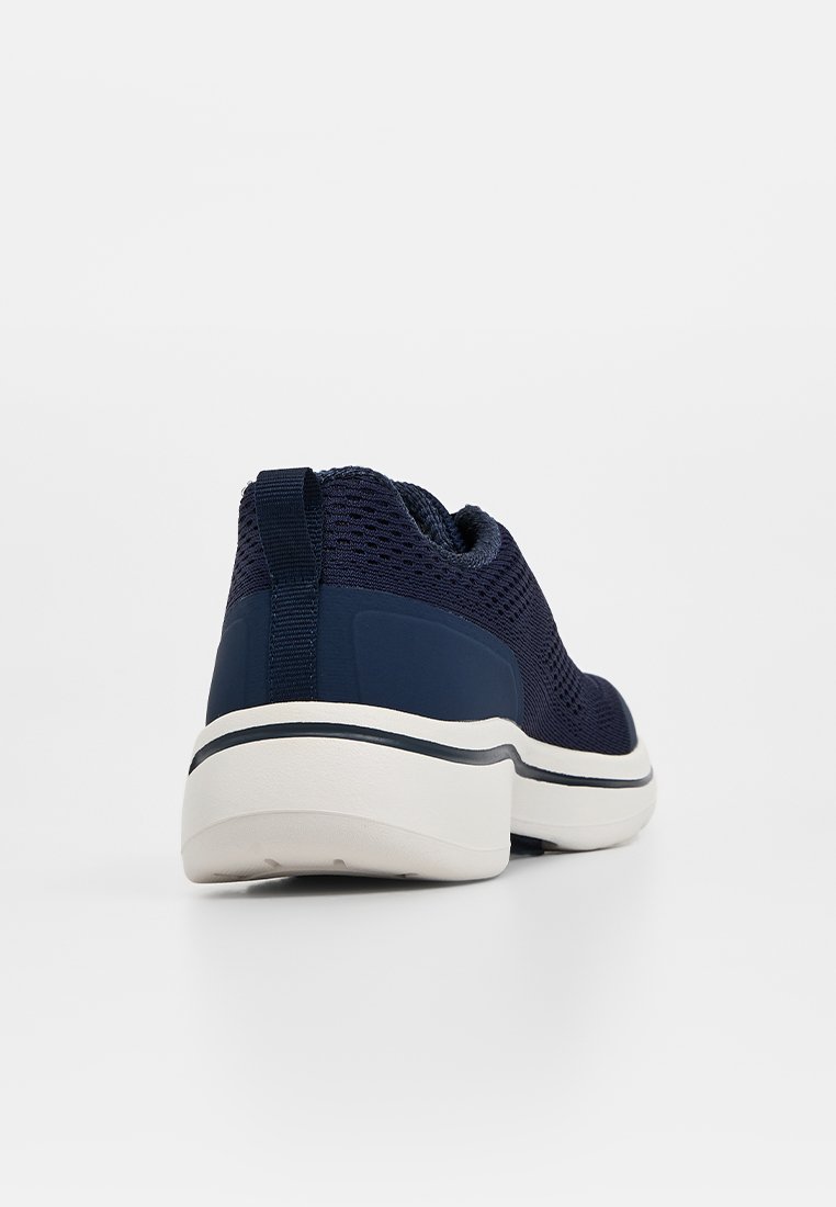 Zapatillas de malla azul marino con una suela intermedia blanca acolchada, parte trasera texturizada y cuello elástico en el tobillo. Cuenta con un tirador para facilitar su puesta.