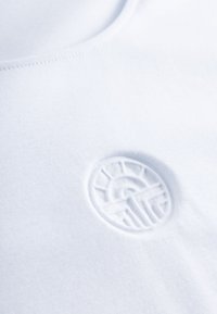 Weißes Baumwoll-T-Shirt mit erhabenem rundem Logo, das ein Sonnen- und Bergmotiv zeigt. Glatte Textur mit Rundhalsausschnitt und sauberer Naht.