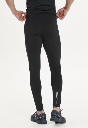 Zwarte sportlegging met een slim fit, voorzien van reflecterende accenten op de kuit en zijzakken. Gemaakt van rekbaar, vochtafvoerend materiaal.