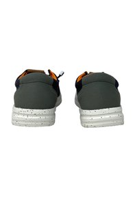 Zapatillas grises con una parte superior lisa, suelas blancas ligeramente moteadas y un interior naranja. Presenta un talón oscuro en contraste y un tirador de cordones.