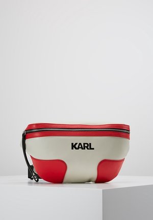 Biała i czerwona skórzana nerka z suwakiem i czarnym logo "KARL" na środku z przodu, umieszczona na białym piedestale na szarym tle.