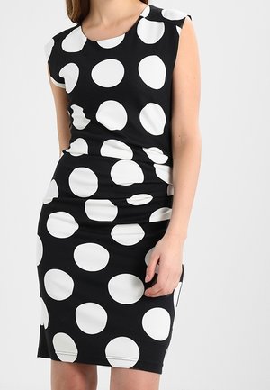 Zwarte jurk met grote witte polka dots. Mouwloos ontwerp, nauwsluitende pasvorm en gladde stof met een lichte glans.