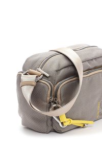 Beige-braune, strukturiert rechteckige Tasche mit beigem Riemen, schwarzen Reißverschlüssen und gelbem Leder-Reißverschlussanhänger vor weißem Hintergrund.