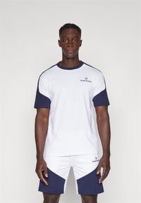 Wit en marineblauw sportt-shirt met korte mouwen, ronde halslijn en logo op de borst, gecombineerd met marineblauwe en witte shorts met schuine accenten.