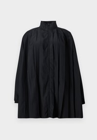 Schwarze übergroße Jacke mit hohem Kragen, Reißverschluss vorne, langen Ärmeln mit elastischen Bündchen und plissierten Details an Vorderseite und Schultern.