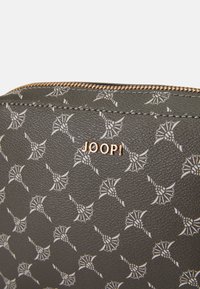 Borsa grigia con motivo a trama, con una superficie testurizzata, caratterizzata da motivi bianchi e dal logo dorato "JOOP!". Chiusura con zip lungo il bordo superiore.