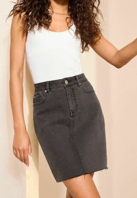 Černá džínová tužková sukně s vysokým pasem, klasickým pětikapsovým designem, roztrhaným lemem a jemnými švy.