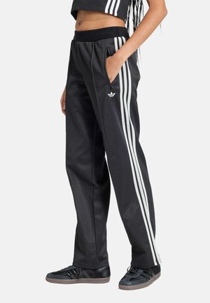 Sorte træningsbukser med en tekstureret finish, med tre hvide lodrette striber på hver side og en elastisk talje.