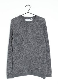 Grauer Strickpullover mit einem strukturierten Muster, Raglanärmeln und einem runden Ausschnitt. Saum und Bündchen sind in einem dunkleren Grau. Hängt an einem schwarzen Haken.