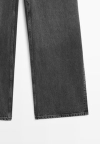 Jambes de jeans en denim noir présentées à plat avec des ourlets larges et droits sur fond blanc.