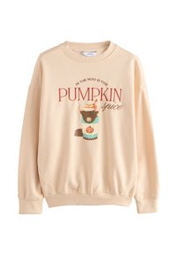 Sweatshirt beige clair avec des épaules tombantes, un col rond et un motif comportant une tasse et le texte « PUMPKIN spice » dans des couleurs contrastantes.