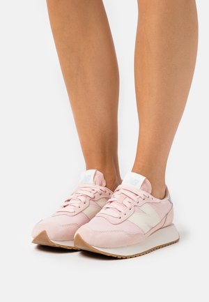 Růžové tenisky z síťoviny a semiše s bílými detaily a tkaničkami. Mají světle zbarvenou podrážku a nenápadné logo na bocích a jazyku.