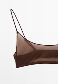 Brun gennemsigtig bralette med tynde, justerbare stropper og minimal dækning. Glat tekstur og trekantet form, der fremhæver et moderne design.