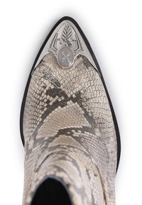 Botte à bout pointu avec un motif de peau de serpent beige et noir, et un embout en métal décoratif argenté orné de motifs gravés.