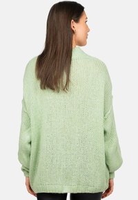 Maglione oversize in verde menta, caratterizzato da una texture chunky, spalle ribassate e polsini a costine. Design minimalista con una vestibilità ampia.