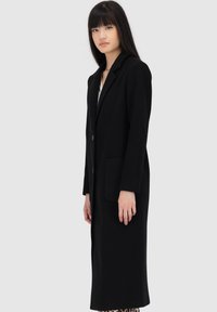 Zwarte wollen jas met een lange silhoet, notch-lapels, twee knopen sluiting en zijzakken, met een soepele textuur en minimalistisch ontwerp.