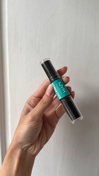 Hand som håller i NYX Wonder Stick, en dubbeländad kontur- och highlighter-pennor med teal etikett mot vit bakgrund.
