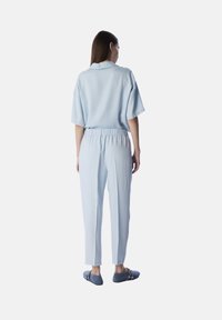 Completo coordinato di un azzurro chiaro, composto da una maglietta a maniche corte morbida e rilassata e da pantaloni con vita elastica, entrambi realizzati in un tessuto liscio e morbido.