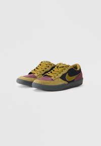 Sapatilhas Nike com uma mistura de camuflagem verde, preto e camurça burdeos, com um acabamento texturizado e logo amarelo, atacadores redondos e sola de borracha.