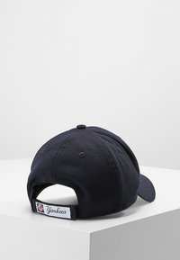 Cappellino da baseball blu navy con tessuto testurizzato, visiera curva, logo ricamato e cinturino regolabile sul retro con etichetta.