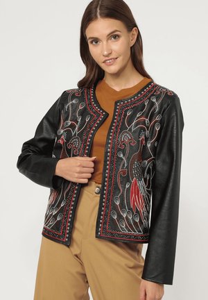 Chaqueta de cuero negra con bordados coloridos de diseños de pavo real. Acentuada con tachuelas a lo largo del escote y el borde. Mangas largas.