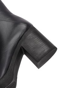 Zwarte leren hoge haklaars met een chunky, structuur hiel. Glad oppervlak met subtiele stikdetails en een gebogen teengevel.