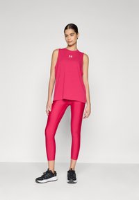 Débardeur de sport rose et leggings, fabriqués en matière extensible. Le débardeur a une encolure ronde, les leggings sont ajustés avec une finition brillante.