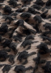 Tessuto a maglia con un motivo a stampa leopardo caratterizzato da colori a contrasto, nero e beige. La texture appare morbida e soffice con accenti rialzati.