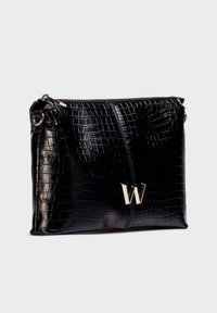 Clutch de piel con textura de cocodrilo negra, con cremallera plateada y emblema metálico "W" en el frente, sobre un fondo neutro.