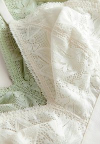 Spets-bh i elfenben och pastellgrön, med blommönster, delikat kant och mjuk textur. Justerbara axelremmar ingår.