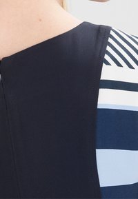 Vestido con un corsé azul marino y mangas a rayas en diferentes tonos de azul y blanco; textura suave; incluye un detalle de cremallera oculta.