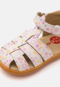 Sandal in pelle bianca con stampa floreale colorata, punta aperta, multiple cinghie, cinturino alla caviglia regolabile e suola in gomma texturizzata.