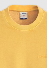 Yellow sweatshirt with ribbed crew neckline. Made of soft cotton, featuring a subtle Levi's logo embroidered on the front. Relaxed fit.