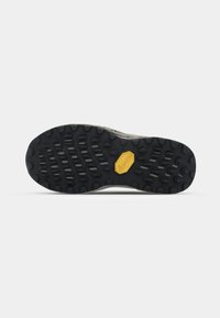 Semelle de chaussure en caoutchouc noir avec un motif texturé et des rainures, arpentée d'un logo de marque hexagonal jaune au centre.