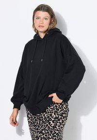 Černá oversized mikina vyrobená z měkké tkaniny, s kapucí na šňůrku a žebrovanými manžetami. V kombinaci s kalhotami s leopardím potiskem.