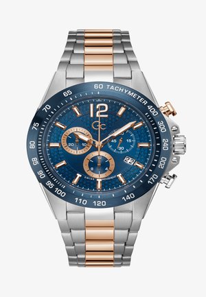 Sidabrinė ir rožinė auksinė chronografo laikrodis su mėlynu tekstūruotu ciferblatu, dideliais skaičiais ir tachimetro skalė ant bezelio. Nerūdijančio plieno apyrankė.