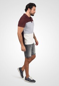 Polo en maroon, gris et blanc en blocs de couleur ; en coton. Associé à un short gris clair et des baskets marine ; design décontracté.