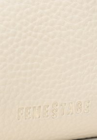Bílá texturovaná kůže s jemně embosovanou značkou "FEMESTAGE." Povrch má měkký, hrbolatý vzhled.