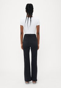 Mustat leveälahkeiset farkut korkean vyötärön kanssa, varustettuna vyölenkillä, kahdella takataskulla ja sileällä puuvillakankaalla. Paritettu valkoisen ribbipaitaan.