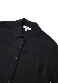 Camicia nera con colletto, chiusura con bottoni davanti, tessuto strutturato da un lato e texture liscia dall'altro.