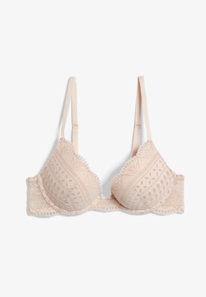 Lace-trimmed, light beige bra with molded cups, adjustable straps, and intricate floral patterns, featuring scalloped edges and soft texture.