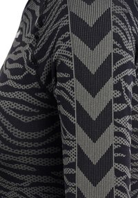 Närbild av ett texturerat tyg med en mörk bakgrund och intrikata grå mönster samt zigzag-ränder som går lodrätt.