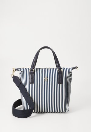 Handtas met verticale strepen in marineblauw en wit, zwarte handvatten, afneembare schouderriem, goudkleurig logo en beslag, afgebeeld op een effen achtergrond.