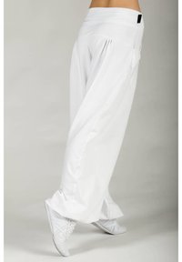 White, loose-fitting pants made of lightweight fabric with a high waistband and side pockets. Paired with white sneakers. Smooth texture.