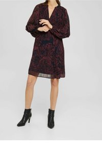 Långärmad klänning i mörk burgundy med blommönster, V-ringning och genomskinligt tyg. Matchad med svarta klackiga ankelskor.