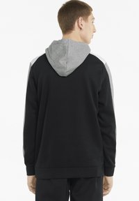 Sudadera negra con capucha y detalles en gris, que presenta un bolsillo tipo canguro, puños acanalados y una textura de felpa suave. La vista trasera muestra los detalles del diseño.