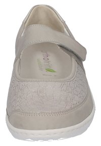 Beige Schuh mit einer strukturierten Oberfläche im Krokodilmuster. Verstellbarer Riemen für einfaches An- und Ausziehen. Weiche Innenausstattung und weiße Gummisohle.